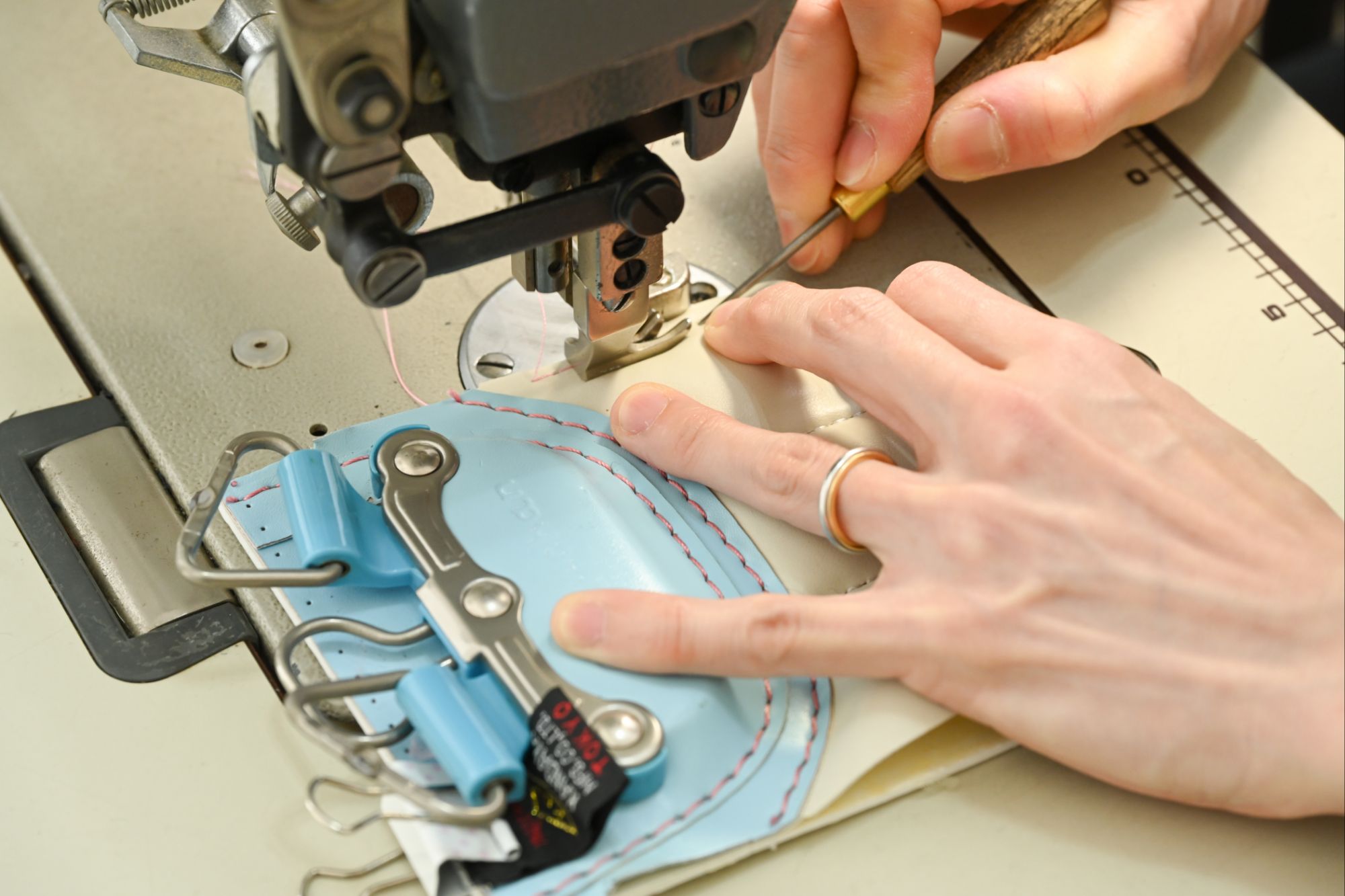 ミニチュアサイズのランドセルにミシンを掛けている写真